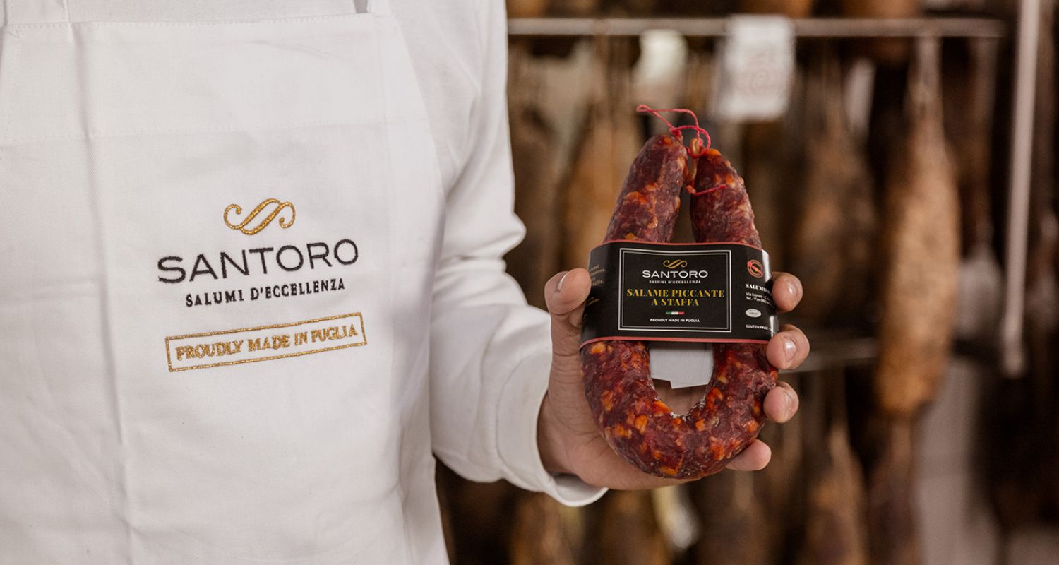 salame piccante a staffa tra le mani di un addetto alla produzione artigianale Santoro